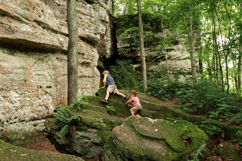 Two boys climbing on mossy rocks